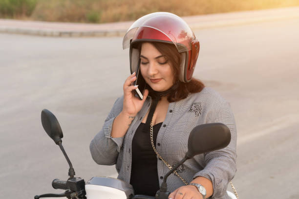 istock Young woman talking by phone on motorcycle 1178841608