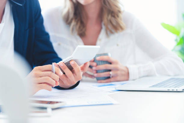 Young Couple working on their home finances. Young Couple working on their home finances. They are working at the dining room table using a calculator. There is some paperwork on the table. Close up tight crop. banking document stock pictures, royalty-free photos & images