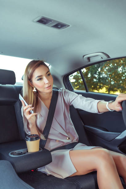 istock woman taxi, asks stop driver while driving, stop demand, communication driver, between passenger taxi driver. Business class, fashionable stylish business, summer spring, autumn, mobile phone, call. 1178845930