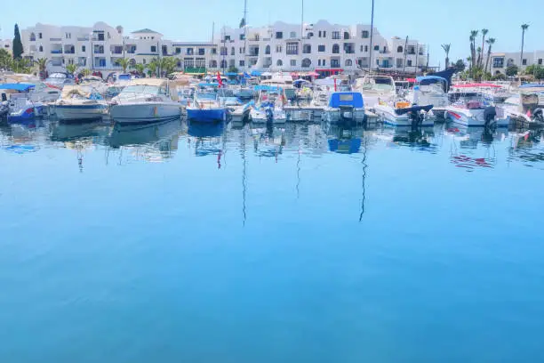 Yachts and boats at the pier on the background of white arabic house at the blue water, copy space