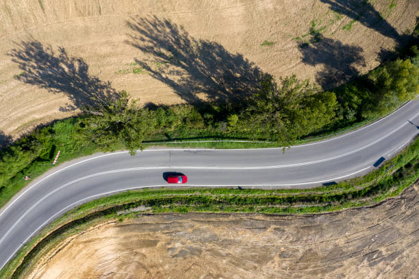 red car on winding road, aerial view - winding road sunlight field cultivated land imagens e fotografias de stock