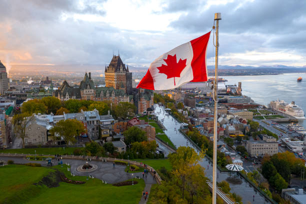 Canadian flag flying over Old Quebec City A flowing Canadian flag on a flagpole. Taken at sunset with Old Quebec City and the St. Lawrence River in the background. Aerial HDR view. canada stock pictures, royalty-free photos & images