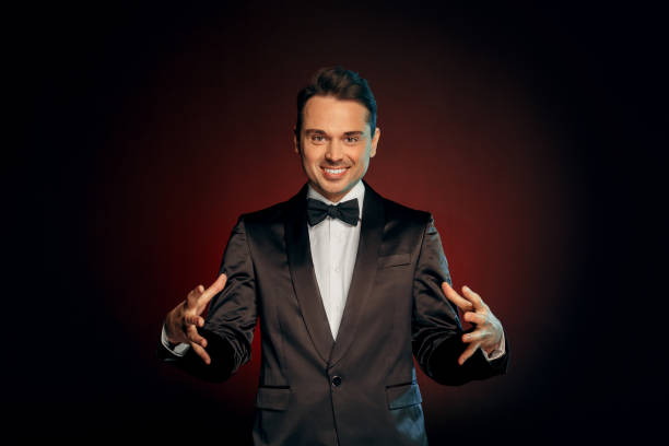 istock Professional Occupation. Showman in suit standing isolated on wall showing trick looking camera happy 1178859994