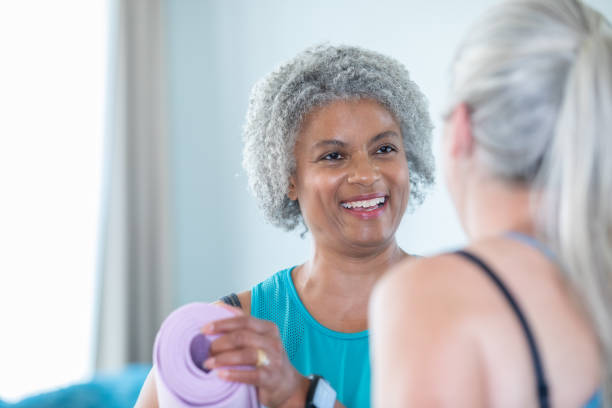 istock Beautiful senior women smiles while talking with yoga instructor before exercise class 1178860022