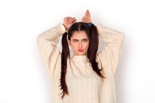 istock Young girl with two ponytails studio standing isolated on white showing rabbit winking playful 1178860079