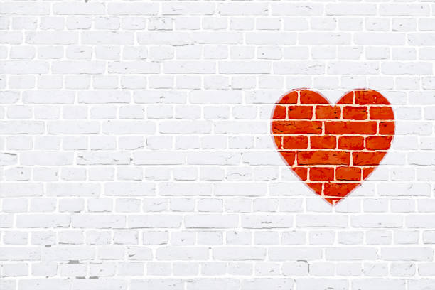 A white colored brick wall with rectangular blocks, textured grungy backgrounds. No text. No people, copy space, copyspace. Vector Xmas background. White colour vintage wall paper with one red colored heart to the right in empty grunge the frame. Simple design in red and white colors. The heart appears to be rubber stamped on wall.