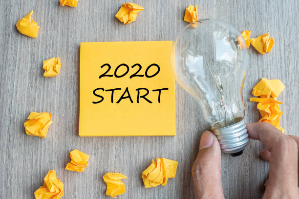 istock 2020 Start words on yellow note and crumbled paper with Businessman holding lightbulb on wooden table background. New Year New Idea Creative, Innovation, Imagination, Resolution and Goal concept 1178871033