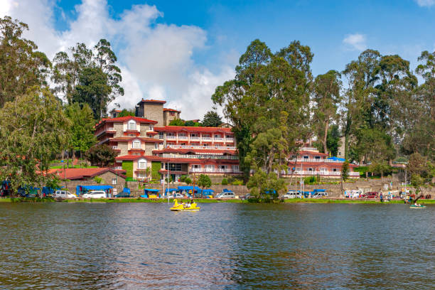 Kodaikanal, South India - Looking From Kodaikanal Lake Towards The Carlton Hotel, In The Colonial Town, In The State Of Tamil Nadu; Several Tourists' Cars Are Parked By The Lakeside. Kodaikanal, India - November 10, 2007: Looking from the Kodaikanal Lake on the Palani Hills, in the South Indian State of Tamil Nadu located at about 7000 feet above mean sea level to the Carlton Hotel. The colonial town and hill station, was set up by the British when they were in India. Several tourists' cars can be seen parked by the lakeside. Some street vendors have stalls set up by the roadside. A couple of boats are seen rowing visitors to the town around the lake. Image shot in the afternoon sunlight; horizontal format. kodaikanal photos stock pictures, royalty-free photos & images