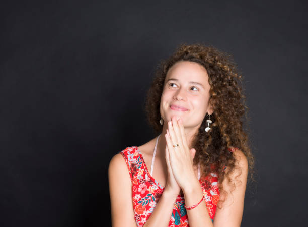 Woman thinking while looking up against black background