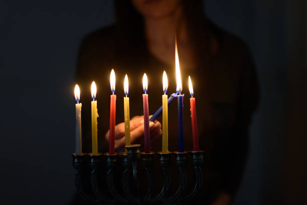 donna ebrea che accende candele hanukkah in una menorah. - hanukkah menorah dreidel judaism foto e immagini stock