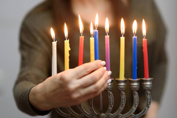 donna ebrea che accende candele hanukkah in una menorah. - hanukkah menorah human hand lighting equipment foto e immagini stock