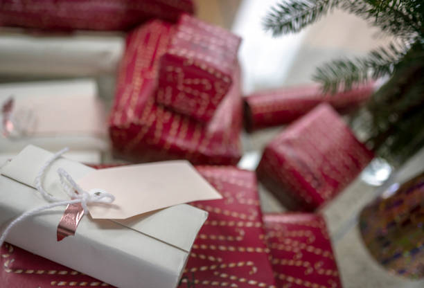 Bright Christmas decorations and gift boxes in holiday wrappers with tags and ribbon folded under the Christmas tree for fun and pleasure Xmas celebration of the whole family together
