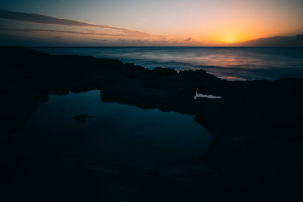 istock Sunset over the ocean with rocky shore 1178884427