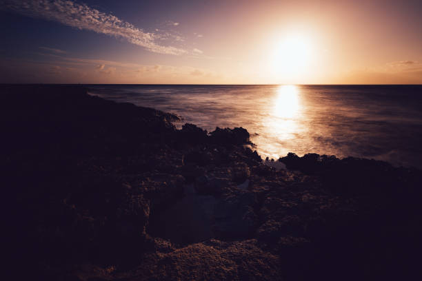 Sunset over the ocean with rocky shore