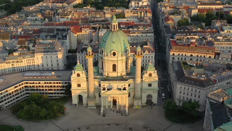 sunset sun light flight over vienna city famous church front park square aerial panorama 4k austria