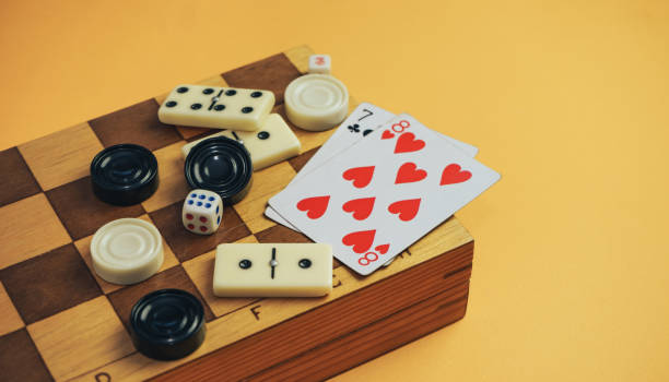 istock Various board games chess board, playing cards, dominoes on a orange background. 1178890475