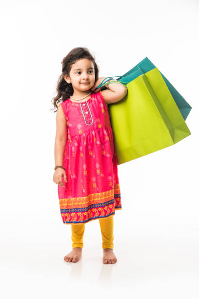 Indian small girl holding shopping bags, standing isolated over white background Indian small girl holding shopping bags, standing isolated over white background beautiful traditional indian girl stock pictures, royalty-free photos & images