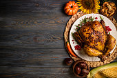 Roasted whole chicken or turkey with autumn vegetables for thanksgiving dinner on wooden background. Thanksgiving Day concept. Top view