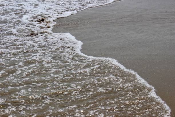 istock Sea waves with bubbles hits the sand beach wallpaper 1178893952