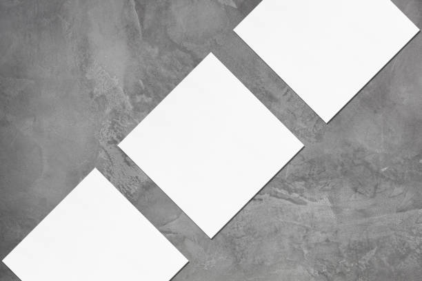 istock Three empty square business card mockups lying diagonally on grey concrete background 1178896292