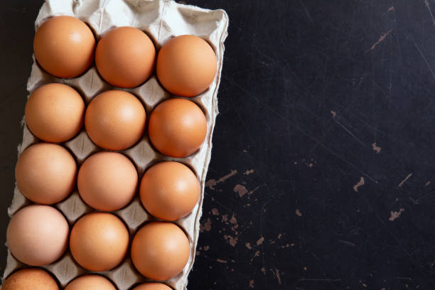 istock Chicken eggs in a cardboard box on black table background. Organic Food.Top view 1178899199
