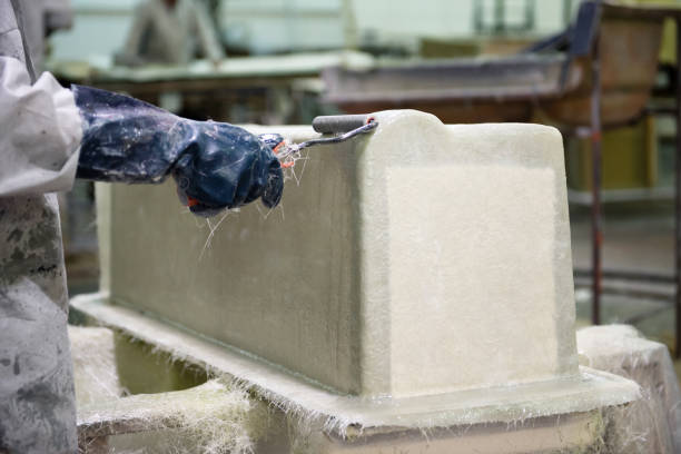 Fiberglass factory worker rolls solution on a fiberglass part Hand of fibreglass factory worker with a roll applying solution on fibreglass part fibreglass stock pictures, royalty-free photos & images