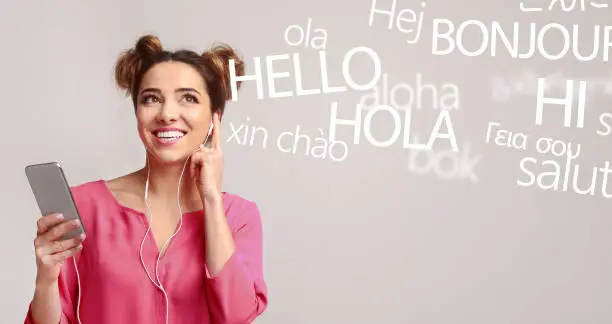Photo of Woman with cellphone hearing different languages on grey