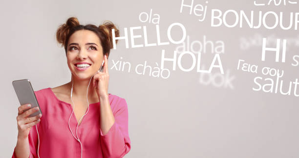 kobieta z telefonem słyszącym różne języki na szarym - text talking translation learning zdjęcia i obrazy z banku zdjęć