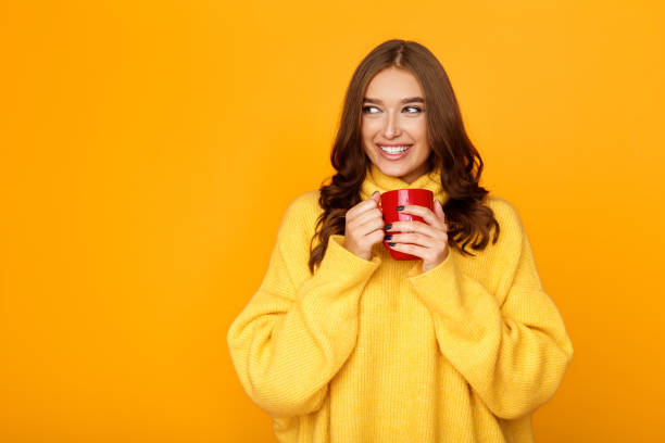 istock Woman wearing sweater and hold cup, orange background 1178902741