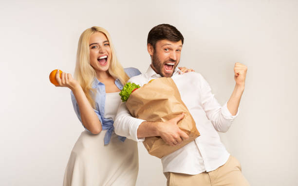 couples retenant le sac d'épicerie gesturing oui sur le fond blanc - green bag paper bag isolated photos et images de collection