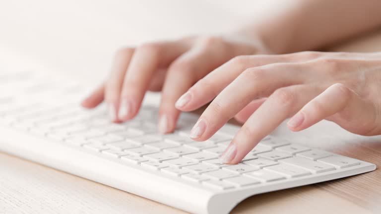 Female hands typing on a white keyboard