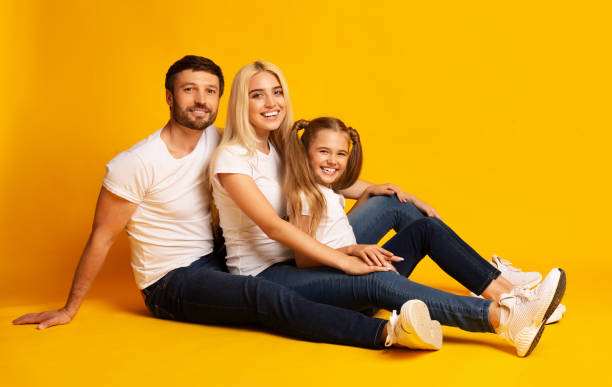 istock Happy Parents And Daughter Sitting On Floor Yellow Background, Studio 1178906825