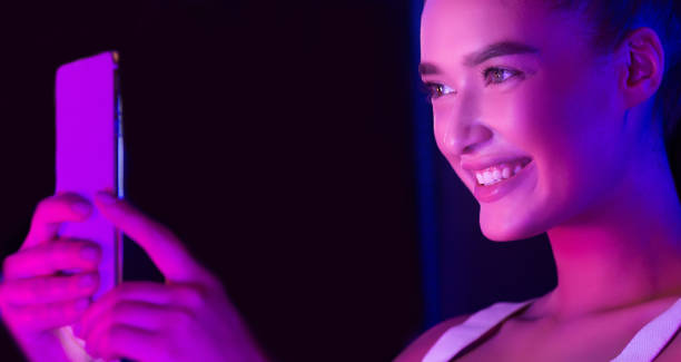 istock Excited woman taking selfie on phone, illuminated by pink light 1178907229