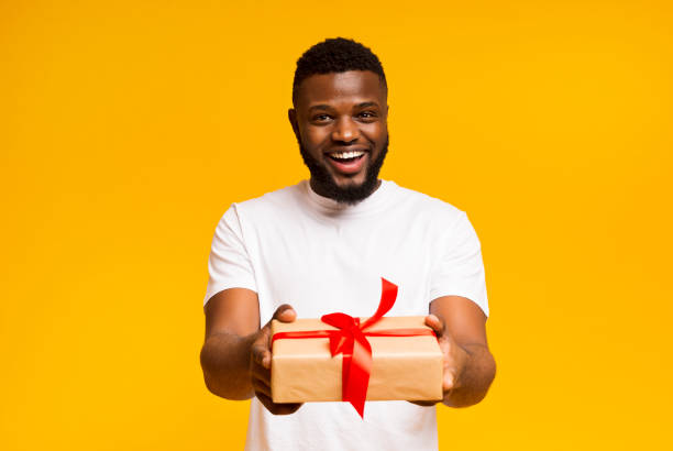 istock Cheerful african american man offering gift box to camera 1178908403