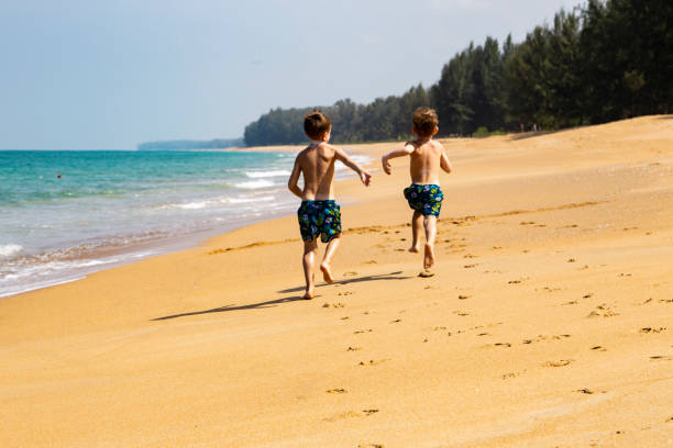2人の少年が砂浜を走る ストックフォト