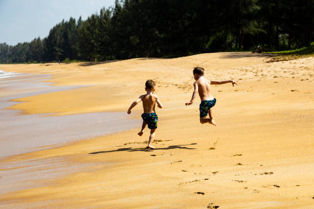2人の少年が砂浜を走る ストックフォト