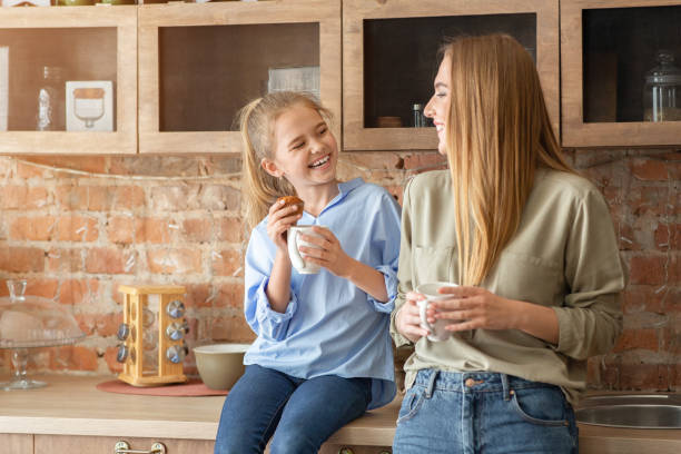 Happy mother and daughter drinking tea at kitchen