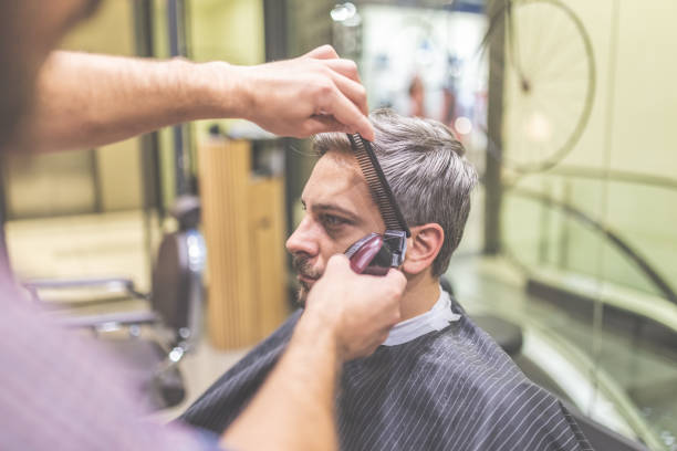 istock Professional barber styling hair of his client by using comb and clipper. 1178910229