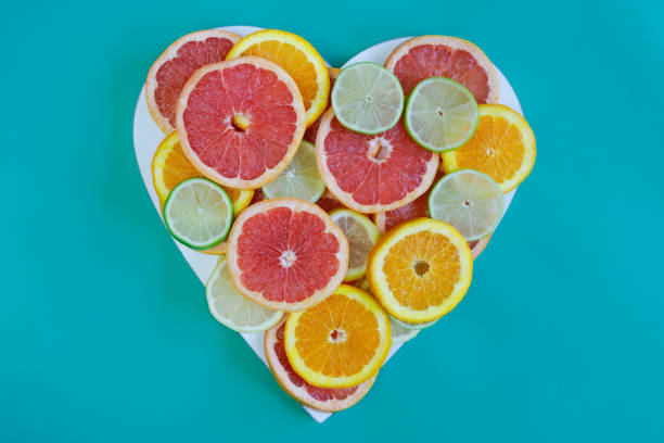 Heart made of citrus slices on blue background.  Grapefruit, orange, lemon and lime.