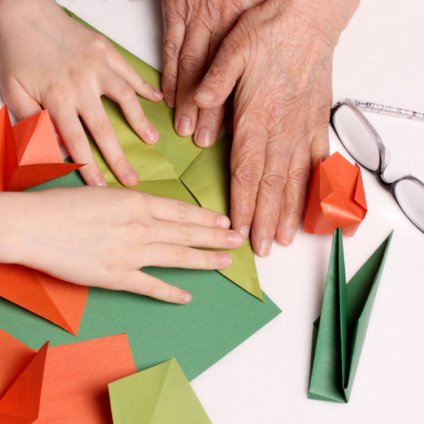 istock baby and grandma make origami 1178910912