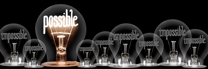 Large group of shining and dimmed light bulbs with fibers in a shape of Impossible and Possible words isolated on black background; concept of Motivation, Success and Change