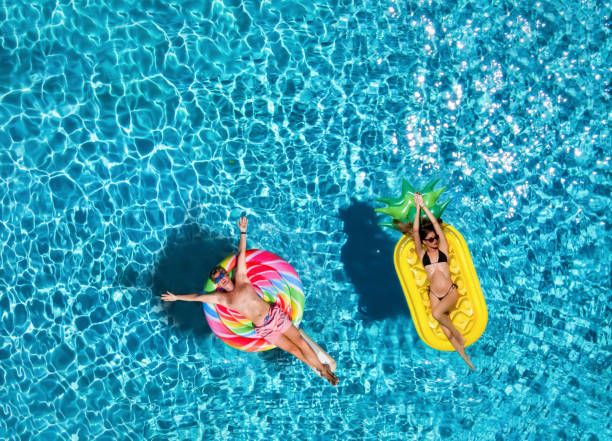 青いプールの水の上にインフレータブルフロート上のカップル - sea swimming greece women ストックフォトと画像