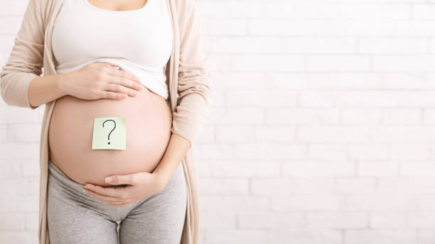 Pregnant woman embracing her belly with question mark on it