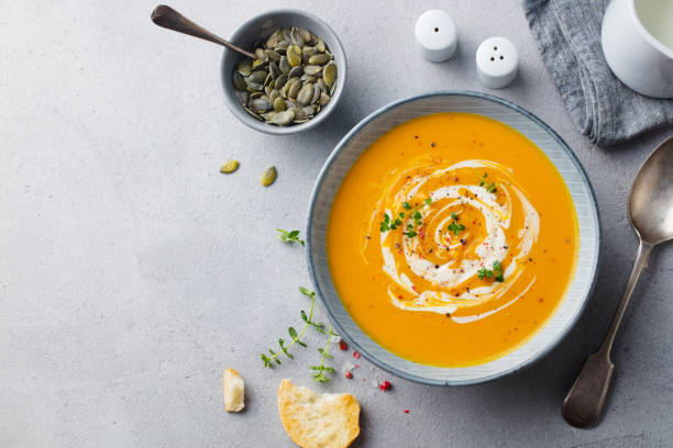 istock Pumpkin and carrot soup with cream on grey stone background. Copy space. Top view. 1178915255