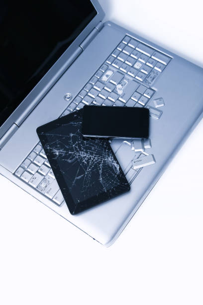 istock A silver laptop with a broken keyboard, tablet with a cracked display and black phone. A close-up picture of part of broken laptop and cracked screen on a tablet. 1178917658