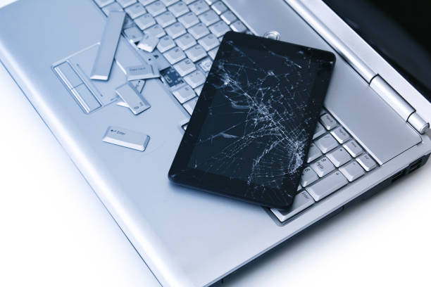 istock A silver laptop with a broken keyboard, tablet with a cracked display. A close-up picture of part of broken laptop and cracked screen on a tablet. 1178917666