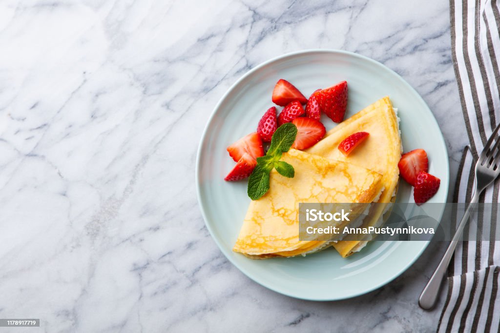 Crepes, thin pancakes with cream cheese, ricotta and fresh strawberries. Marble background. Top view. Copy space. Crepes, thin pancakes with cream cheese, ricotta and fresh strawberries. Marble background. Top view. Copy space Crêpe - Pancake Stock Photo