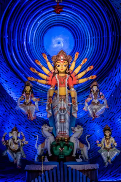 Goddess Durga idol at decorated Durga Puja pandal, shot at colored light, at Kolkata, West Bengal, India. Durga Puja is biggest religious festival of Hinduism and is now celebrated worldwide.