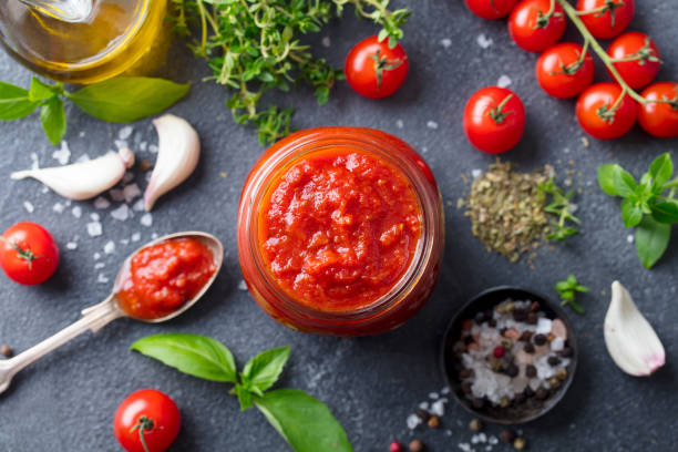 tomato sauce in a glass jar with fresh herbs, tomatoes and olive oil. top view. slate background. - restaurant pasta italian culture dinner imagens e fotografias de stock