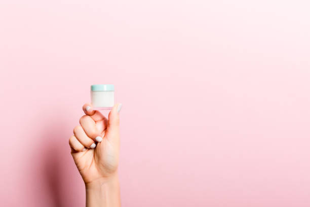 여성 손 들고 크림 병 의 로션 분리. 소녀 주기 항아리 화장품 에 핑크 배경 - jar human hand moisturizer packaging 뉴스 사진 이미지